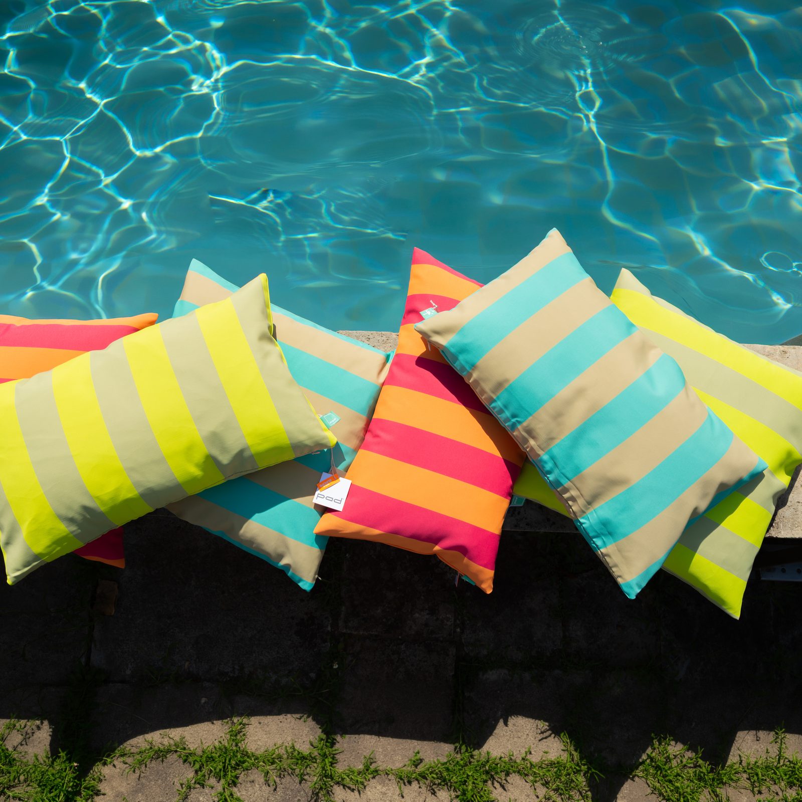 Bunte PAD Outdoorkissen am Poolrand mit türkisem Wasser – Sommer-Shooting 2026